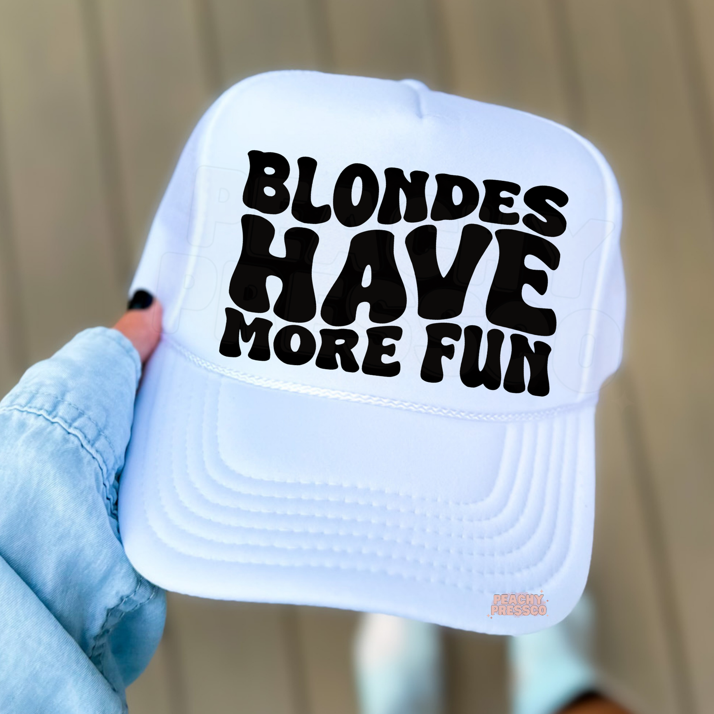 White trucker hat with bold “Blondes Have More Fun” text.