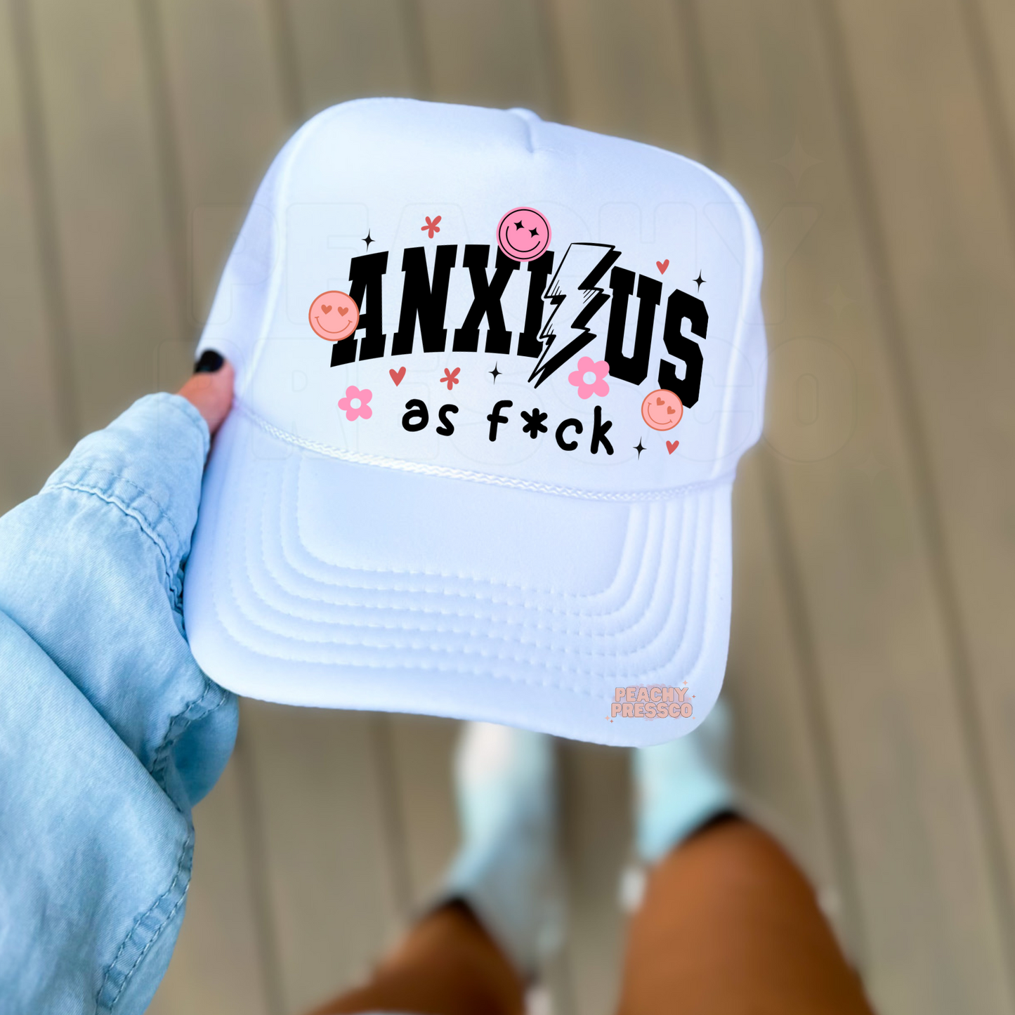 White foam trucker hat with a bold "Anxious as Fck" graphic featuring a lightning bolt, pink smiley faces, flowers, and hearts. Cute humorous trucker hat with trendy coquette-inspired details.*