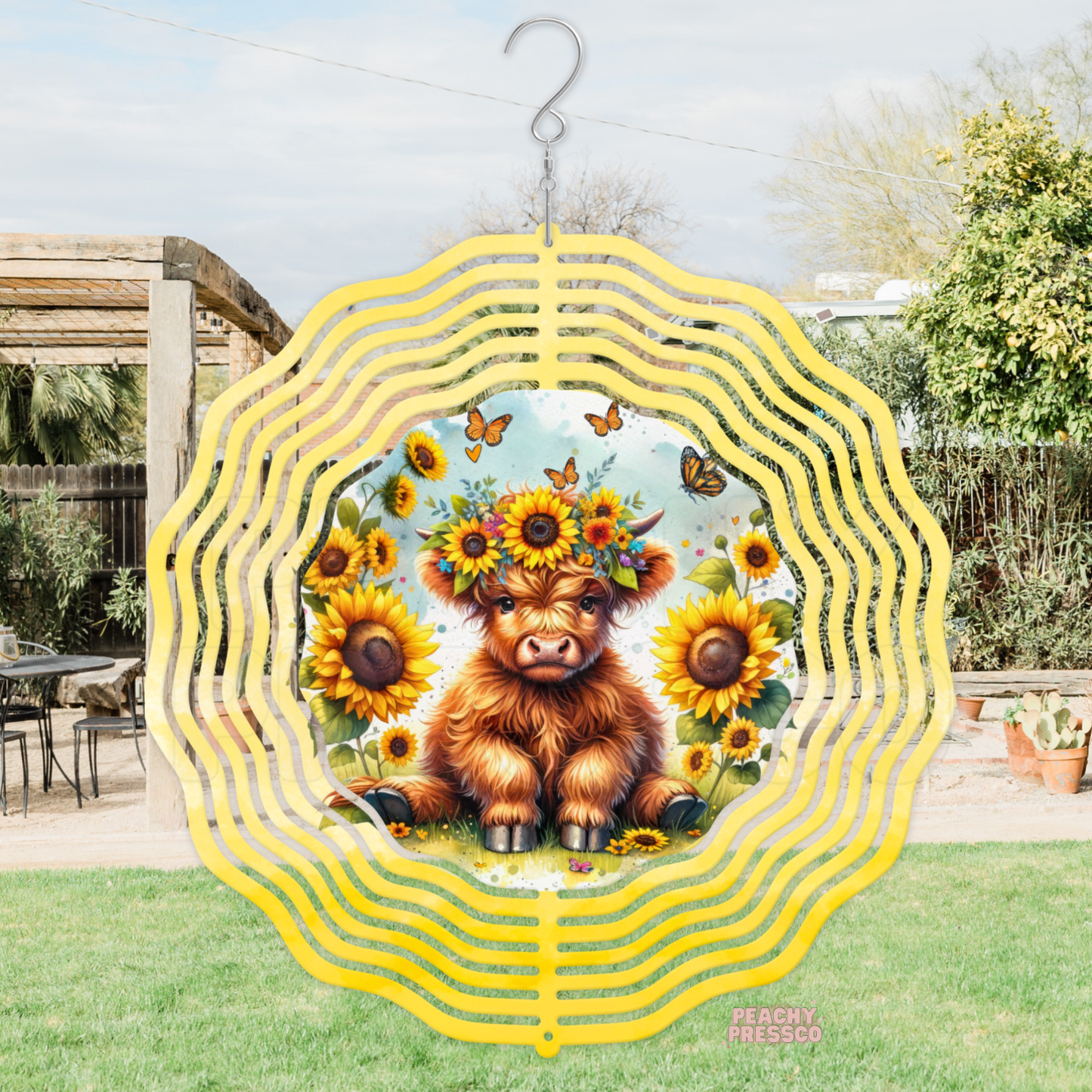 Charming metal wind spinner featuring an adorable baby Highland cow wearing a sunflower flower crown with butterflies and blooming sunflowers.