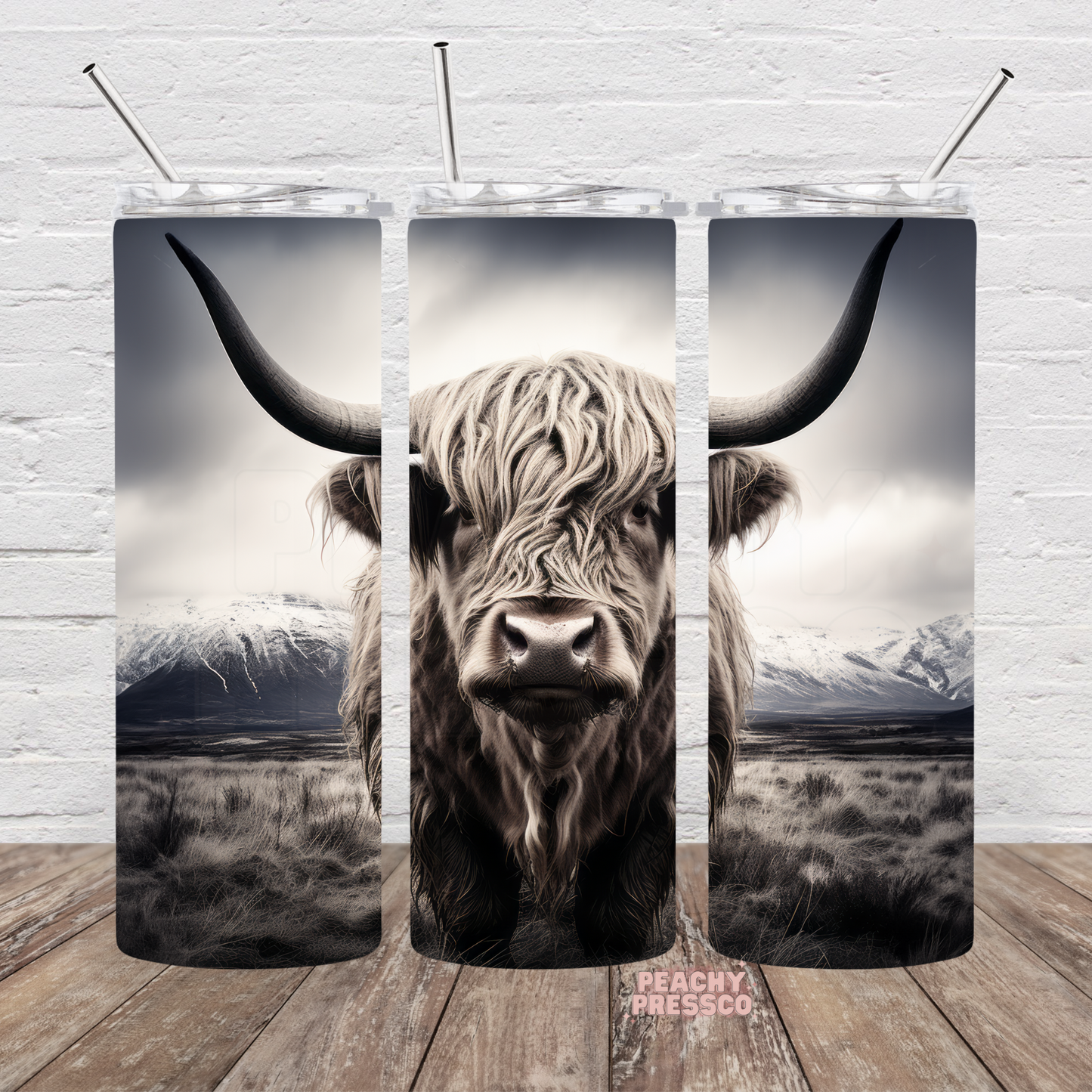 Black and white Highland cow standing before snow-covered mountains on a full wrap 20oz skinny tumbler.