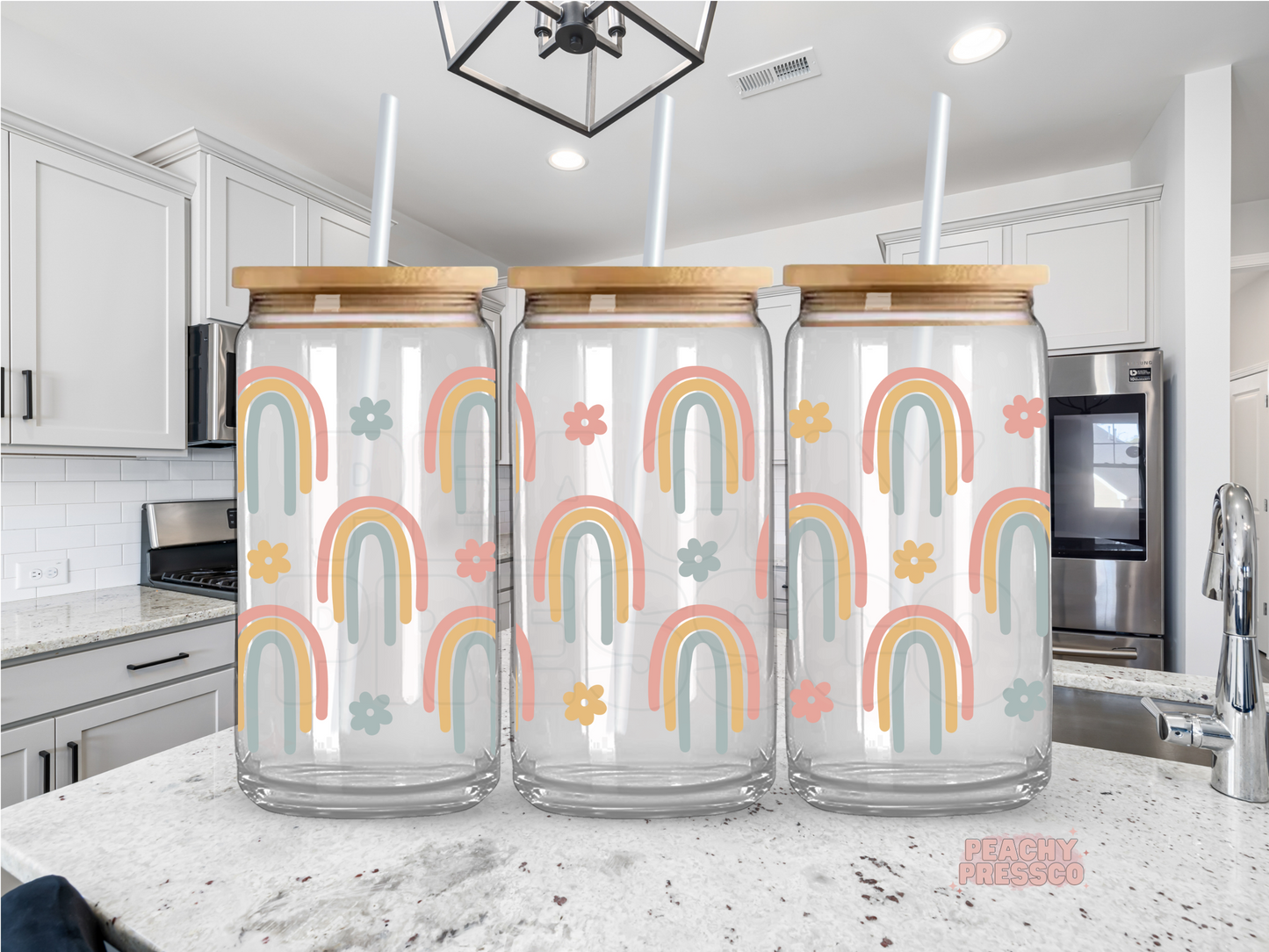 16 oz glass cup featuring a repeating pattern of pastel rainbows and small retro flowers with a bamboo lid and reusable glass straw.