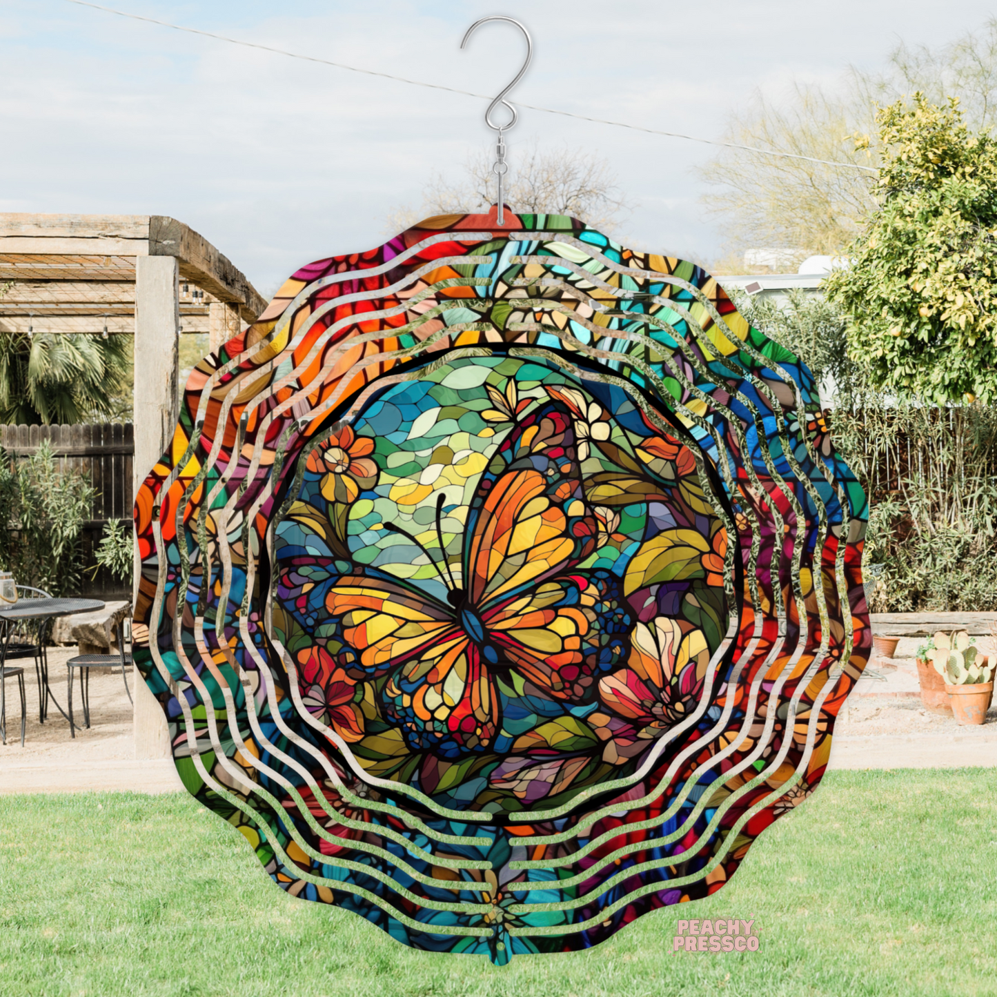 Colorful stained glass inspired metal wind spinner featuring a vibrant butterfly surrounded by mosaic flowers and intricate floral patterns for outdoor décor.