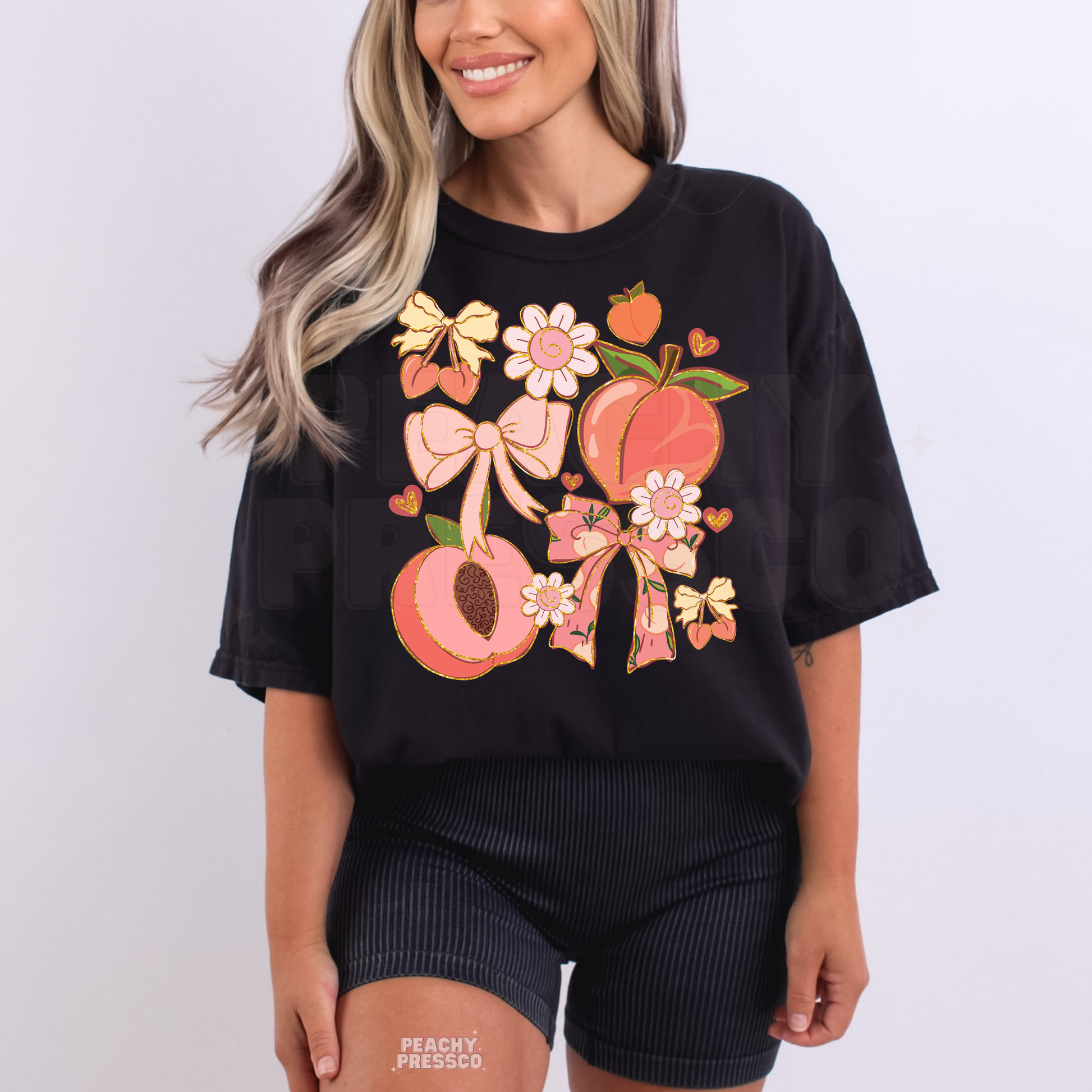 Woman wearing a black oversized t-shirt with feminine peach and floral graphic featuring bows and hearts.