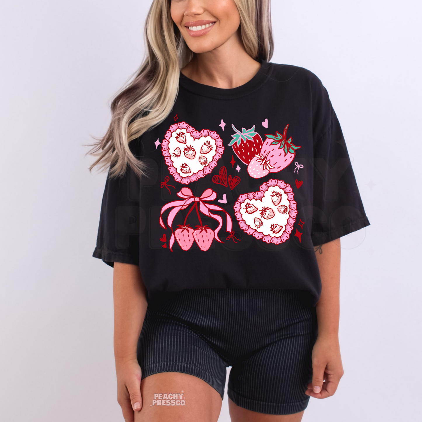 Woman wearing oversized black t-shirt with pink strawberry, bow, and heart coquette aesthetic graphic print.