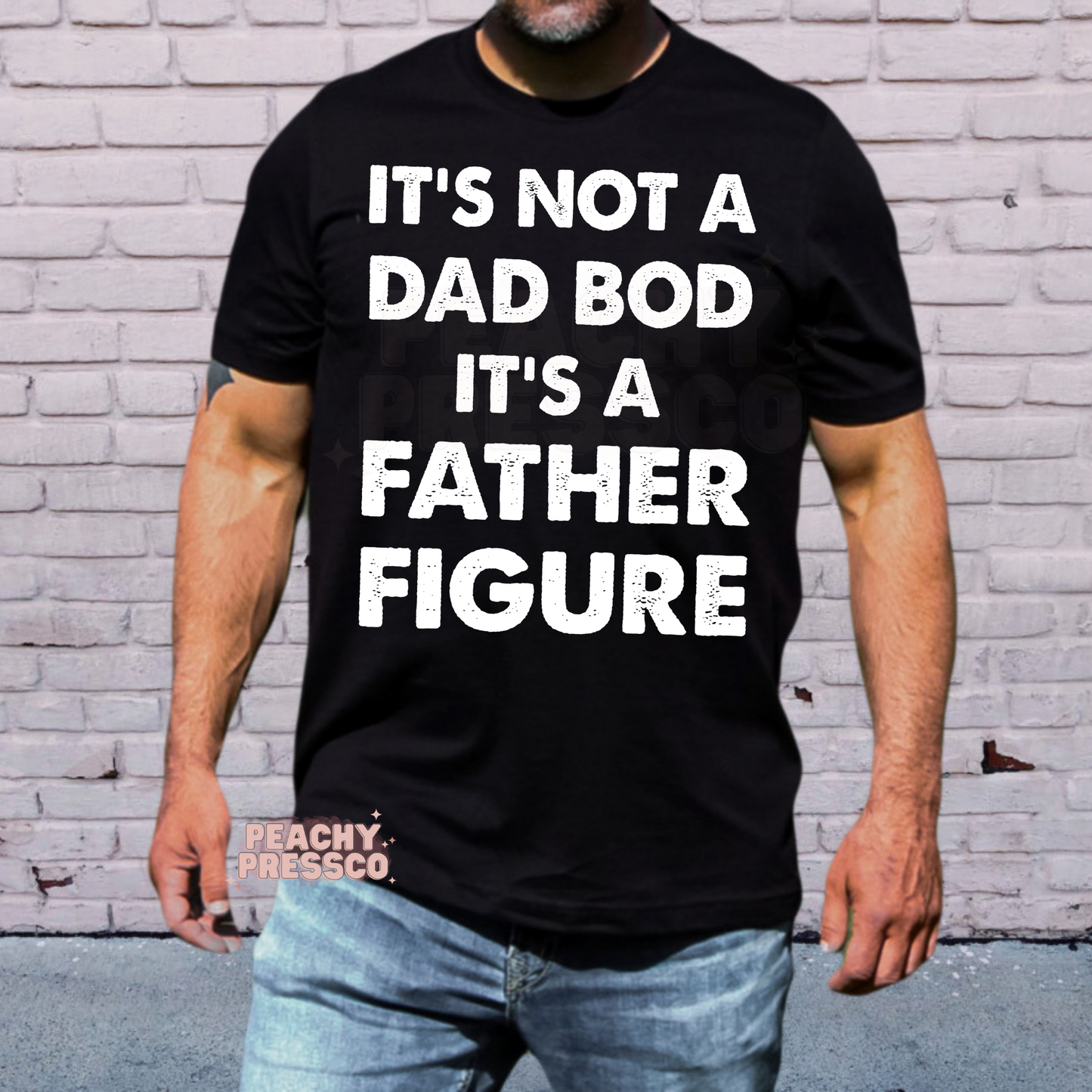 Man wearing black t-shirt with bold white “It’s Not a Dad Bod It’s a Father Figure” slogan graphic.