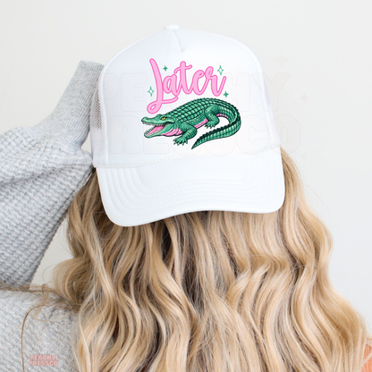 White trucker hat featuring pink “Later” script with a colorful alligator graphic, styled for lake days, southern summer outfits and coastal vibes.