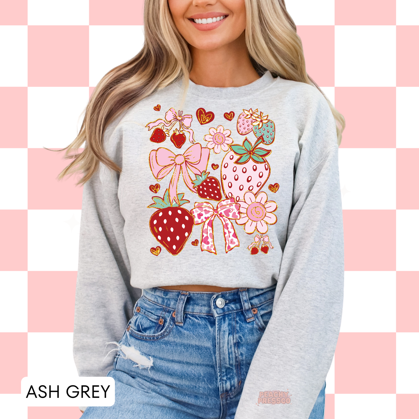 Woman wearing an ash grey sweatshirt featuring a girly strawberry collage design with bows, flowers, and heart accents in coquette style.