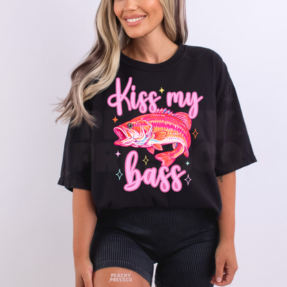 Woman wearing a black oversized graphic t-shirt featuring a colorful bass fish artwork and “Kiss My Bass” phrase for lake days and outdoor adventures.