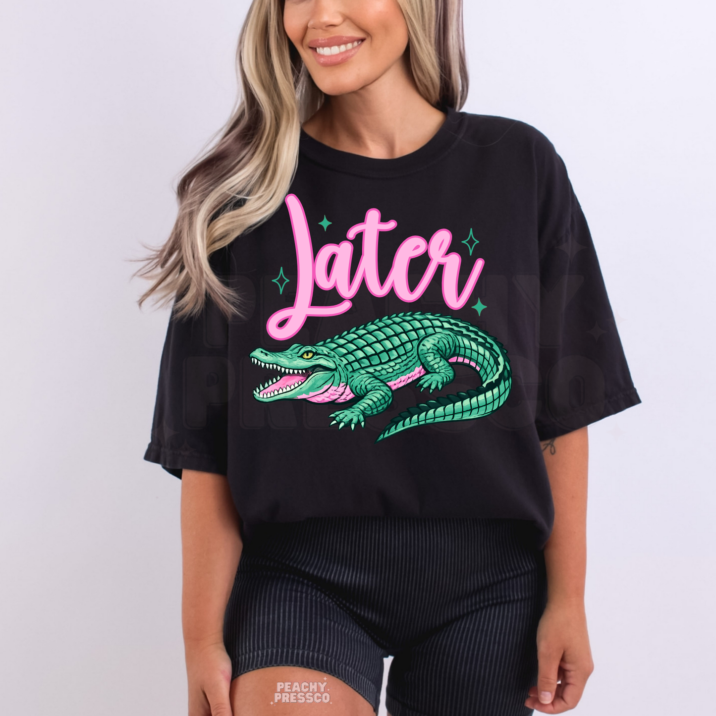 Black oversized graphic t-shirt featuring pink “Later” text and teal alligator artwork – playful women’s beach and lake life apparel.
