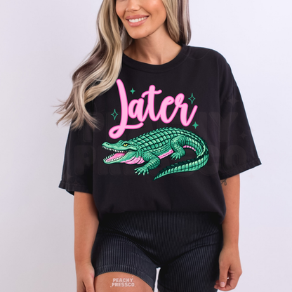 Black oversized graphic t-shirt featuring pink “Later” text and teal alligator artwork – playful women’s beach and lake life apparel.
