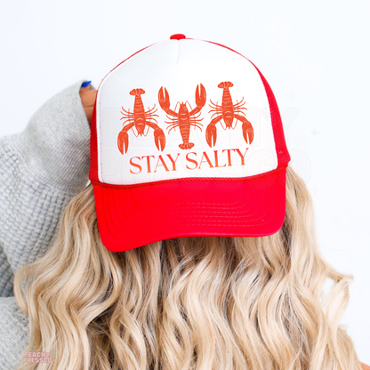 Red and white trucker hat featuring a vintage lobster graphic and “Stay Salty” text, perfect for coastal style, beach vacations, lake days and summer outfits.