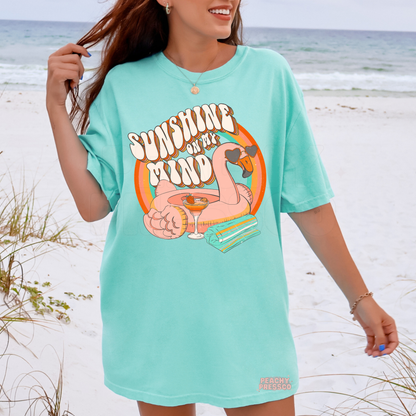 Woman wearing an island reef oversized beach t-shirt with retro flamingo float graphic, tropical drink, and rainbow summer artwork.