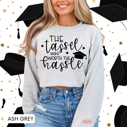 Ash grey graduation crewneck with The Tassel Was Worth the Hassle design, graduation cap artwork, and motivational grad quote.