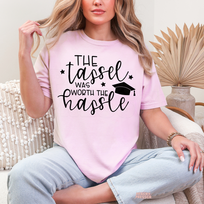 Cute pink graduation t-shirt with The Tassel Was Worth the Hassle saying and graduation cap design for Class of 2026 graduates.
