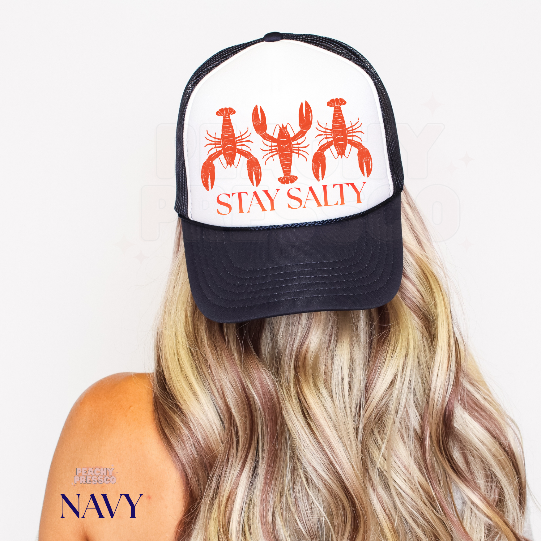 Navy and white trucker hat with retro lobster illustration and “Stay Salty” design, a playful coastal trucker hat for beach days and summer adventures.