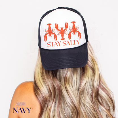 Navy and white trucker hat with retro lobster illustration and “Stay Salty” design, a playful coastal trucker hat for beach days and summer adventures.