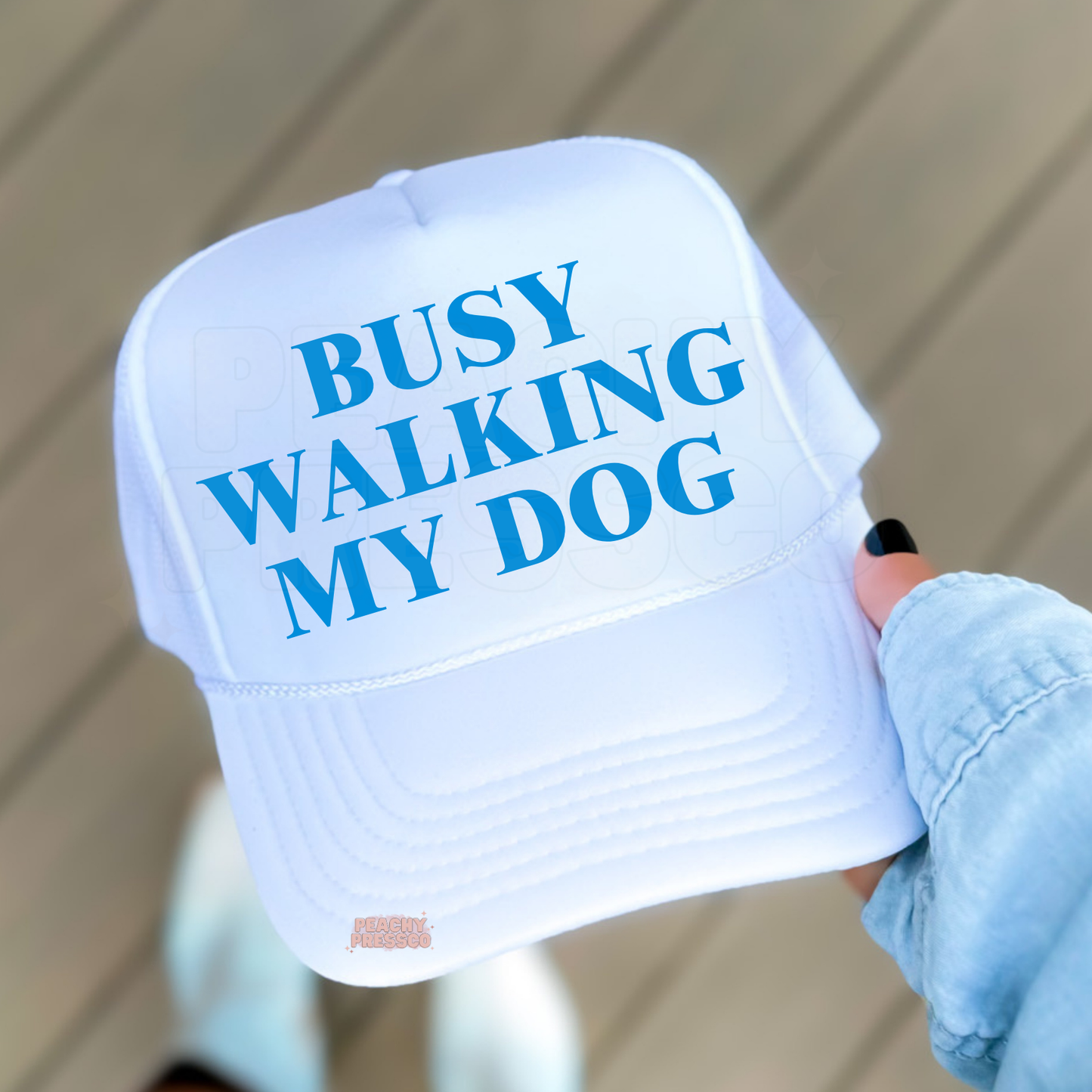 White with Blue trucker hat featuring “Busy Walking My Dog” text.
