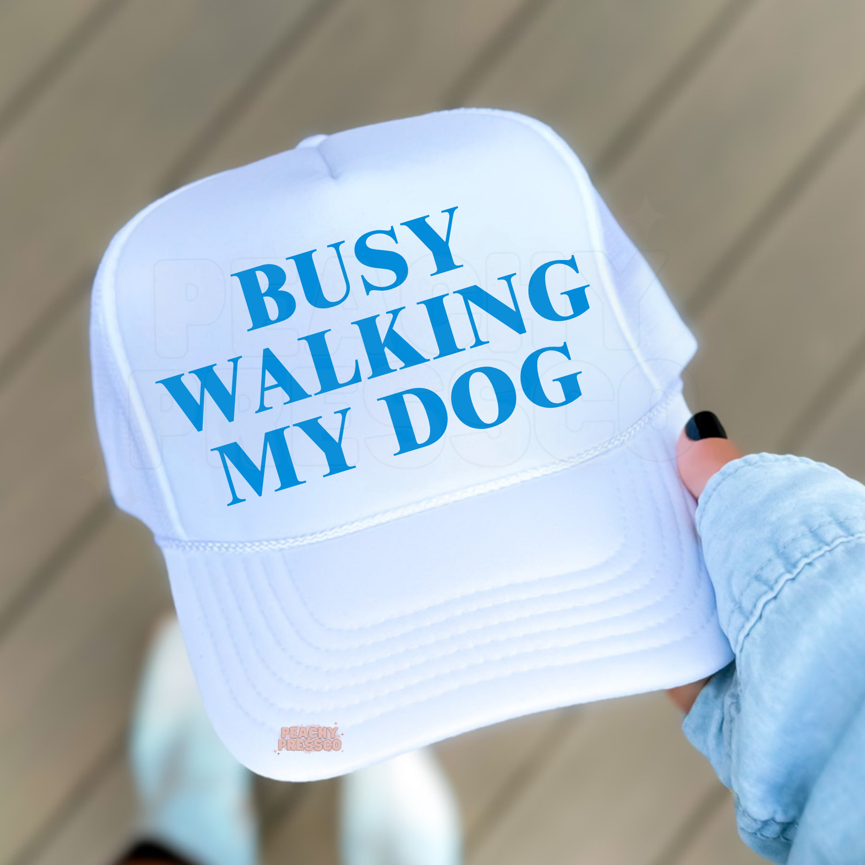 White with Blue trucker hat featuring “Busy Walking My Dog” text.
