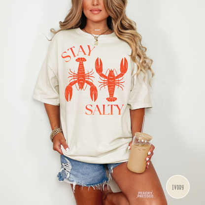 Ivory oversized graphic t-shirt featuring vintage lobster artwork and “Stay Salty” text – coastal vacation shirt for women.