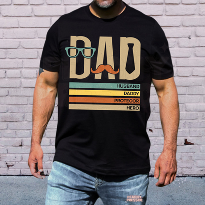 Man wearing black t-shirt with retro “Dad” graphic featuring glasses, mustache, tie, and funny fatherhood text design.