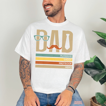 Man wearing white t-shirt with retro dad graphic featuring glasses, mustache and tie icons.
