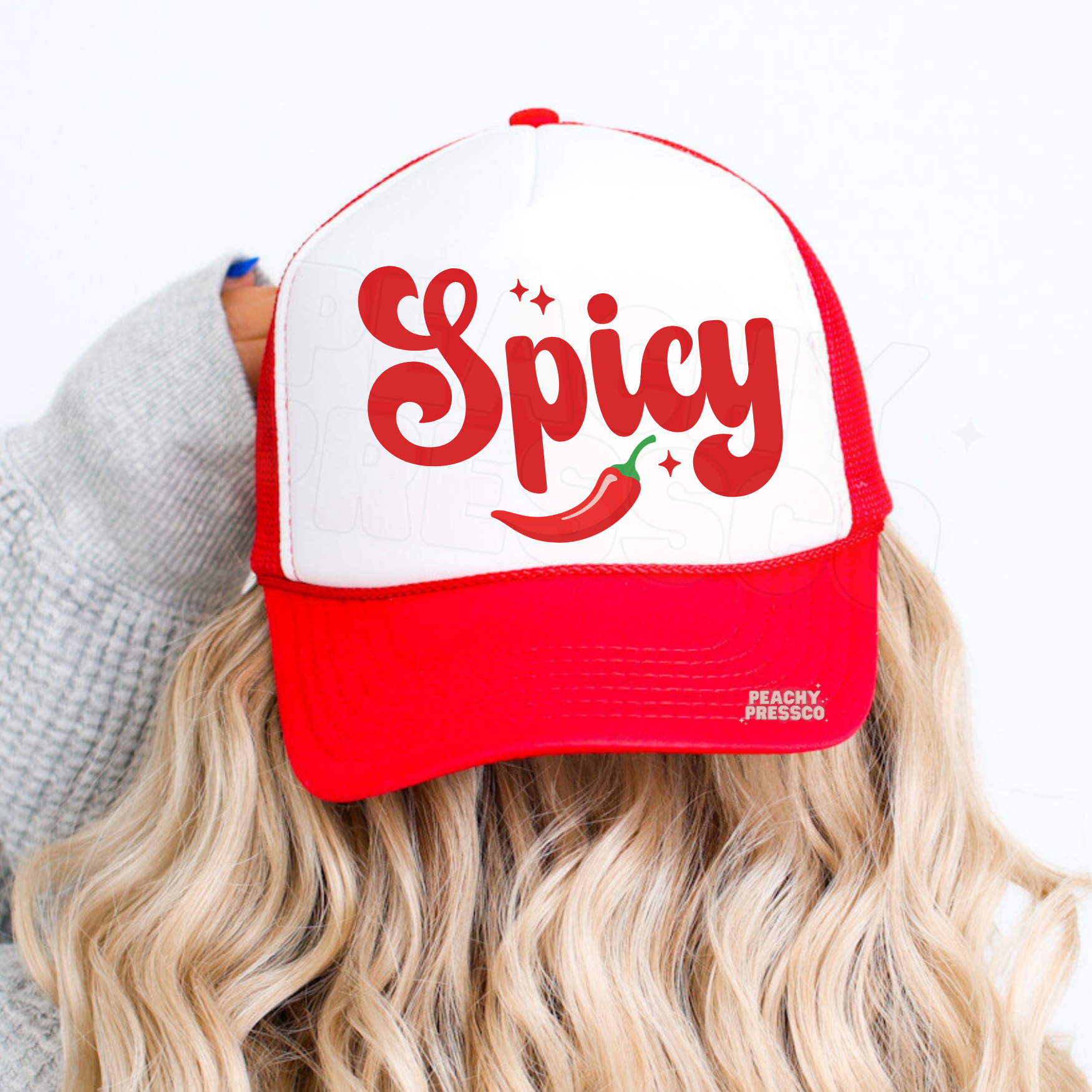 Woman wearing red and white trucker hat with “Spicy” text and chili pepper graphic. Cute trendy women’s trucker cap for summer outfits, country concerts and casual style.