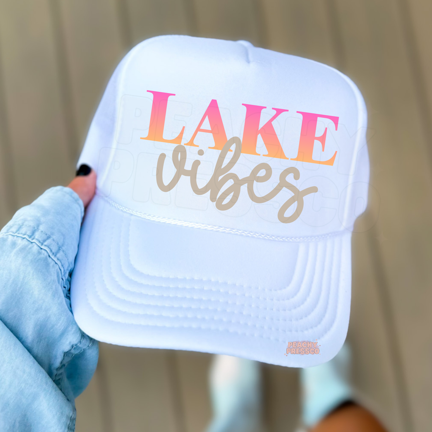 Women’s white Lake Vibes trucker hat with pink sunset lettering – trendy lake life accessory for vacations and outdoor summer style.