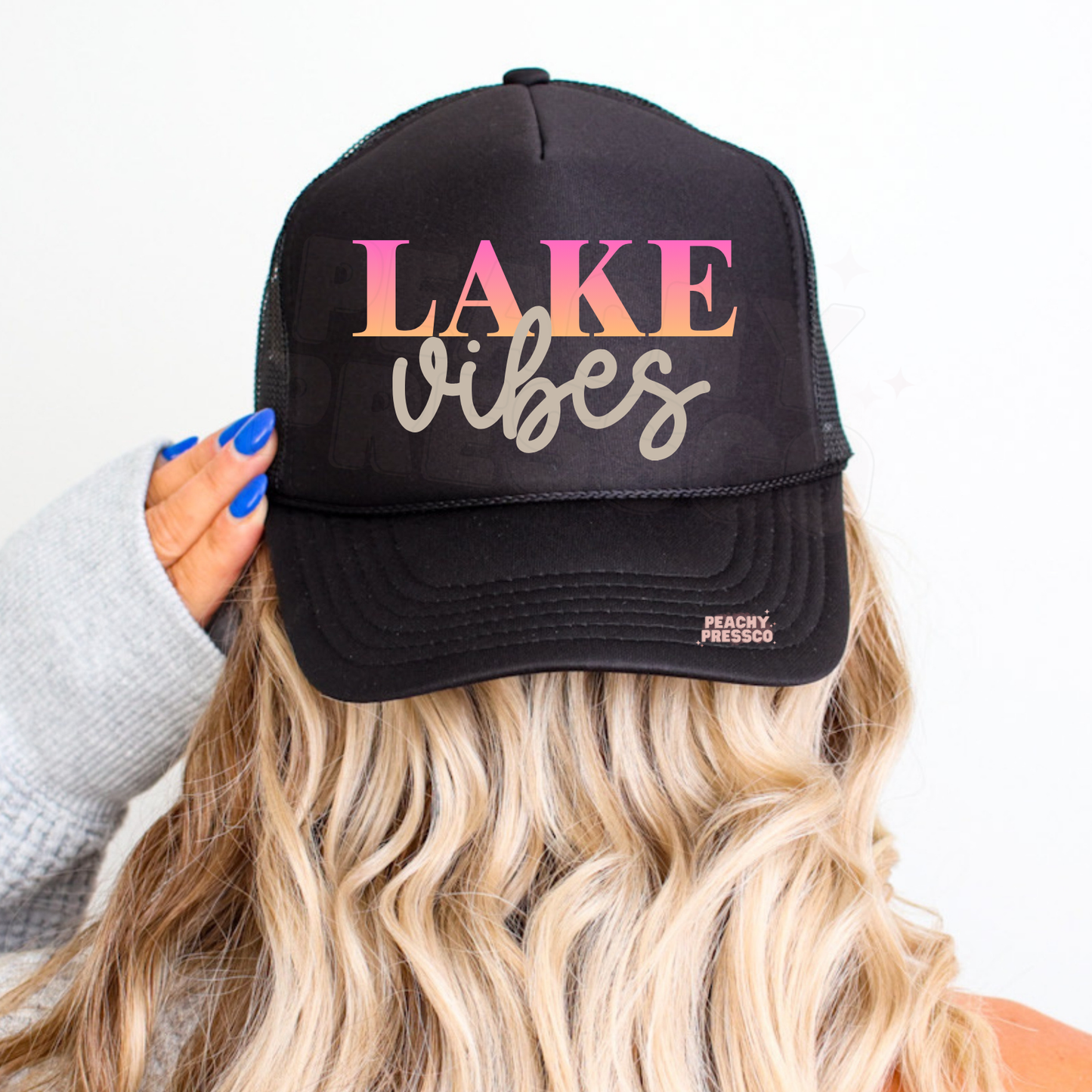 Black trucker hat with Lake Vibes sunset graphic in pink and neutral tones – trendy women’s lake life hat for summer, boating and beach days.