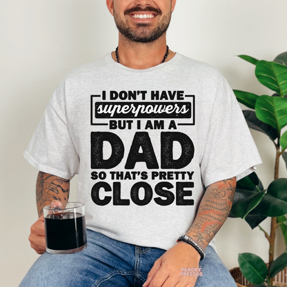 Man modeling ash grey t-shirt featuring bold black typography reading “I Don’t Have Superpowers But I Am a Dad So That’s Pretty Close.”