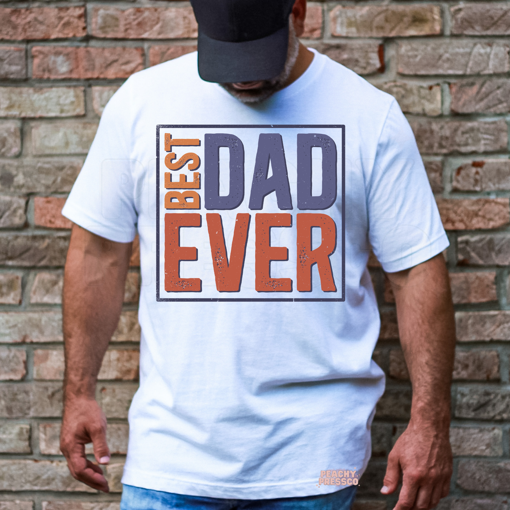 Man wearing white t-shirt with retro “Best Dad Ever” typography graphic in muted vintage colors.
