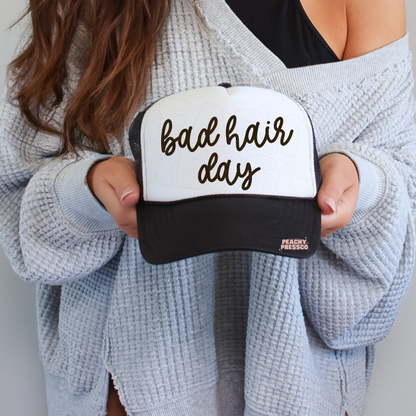 Black and white trucker hat featuring handwritten “Bad Hair Day” graphic.