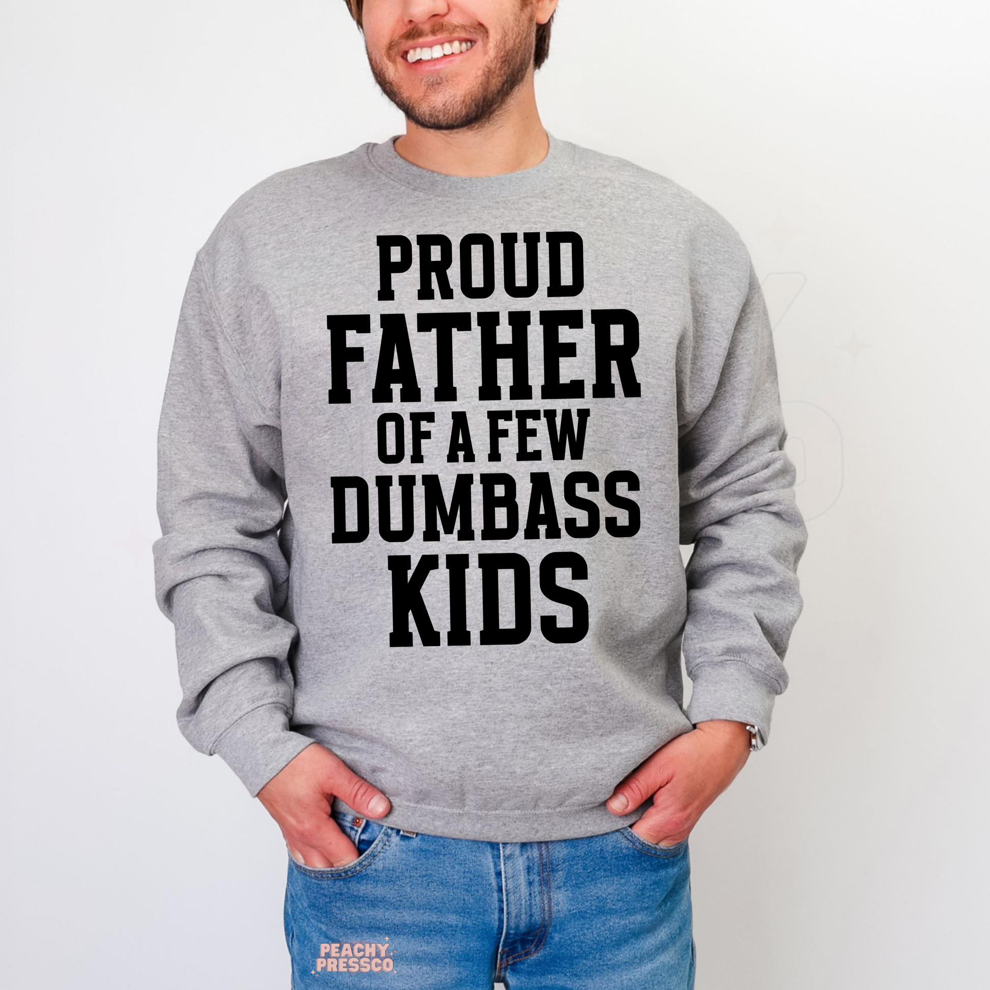 Man modeling grey crewneck sweatshirt featuring large black “Proud Father of a Few Dumbass Kids” slogan print.