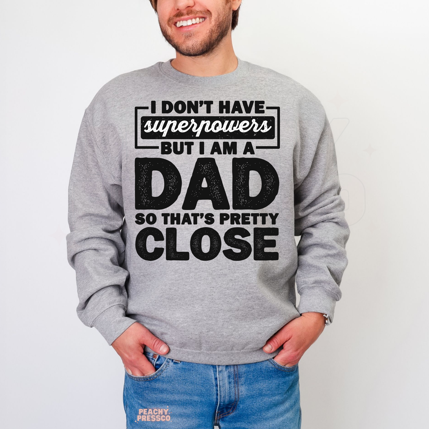 Smiling man in grey crewneck sweatshirt with funny fatherhood quote design and oversized bold typography print.