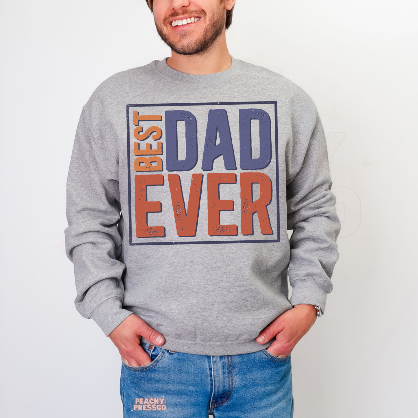 Man wearing grey crewneck sweatshirt with vintage “Best Dad Ever” typography graphic in blue and orange lettering.