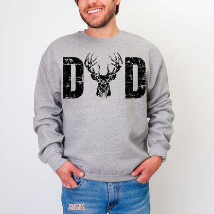Man modeling grey crewneck sweatshirt with bold distressed “DAD” hunting graphic featuring buck deer illustration.