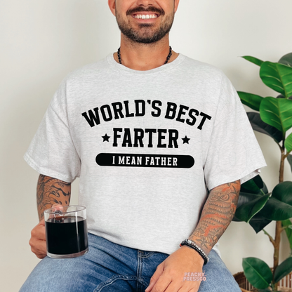 Man sitting indoors wearing ash grey t-shirt with humorous “World’s Best Farter I Mean Father” dad shirt design.