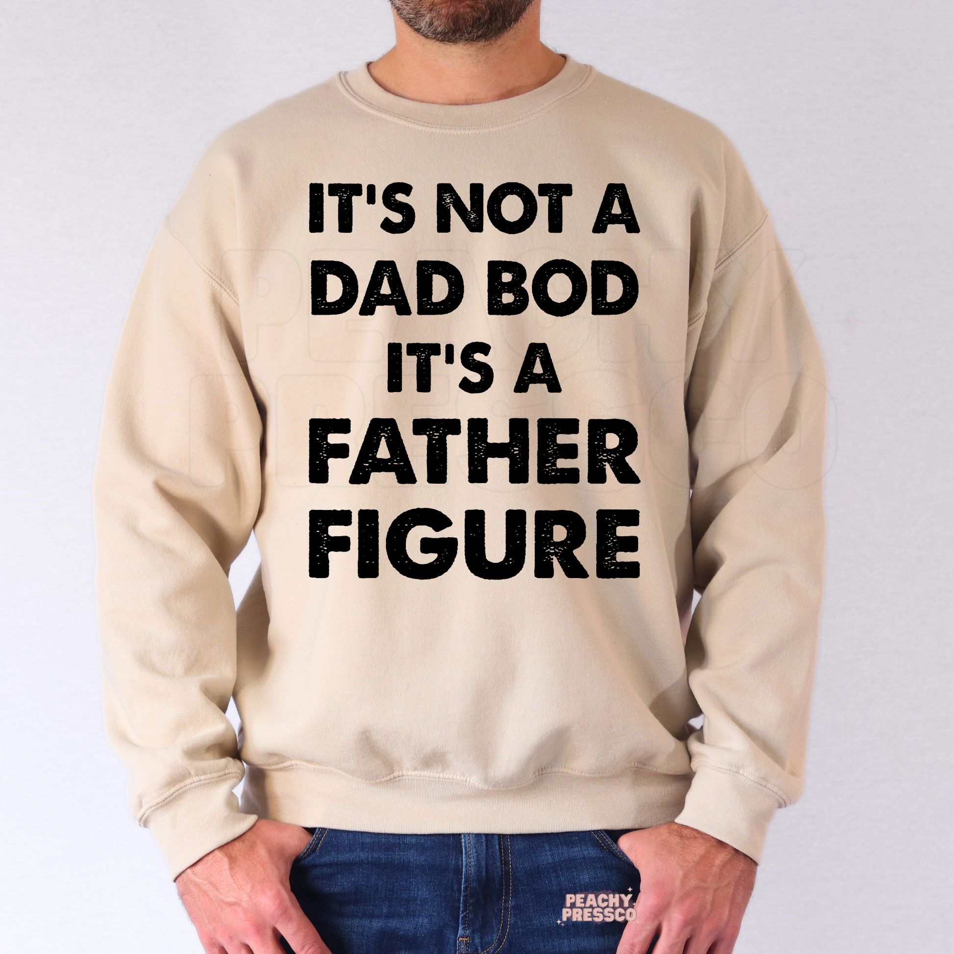 Man modeling beige crewneck sweatshirt with bold “It’s Not a Dad Bod It’s a Father Figure” typography design.