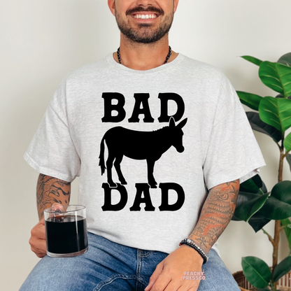 Man wearing ash grey t-shirt featuring black “Bad Dad” typography and donkey silhouette graphic design.