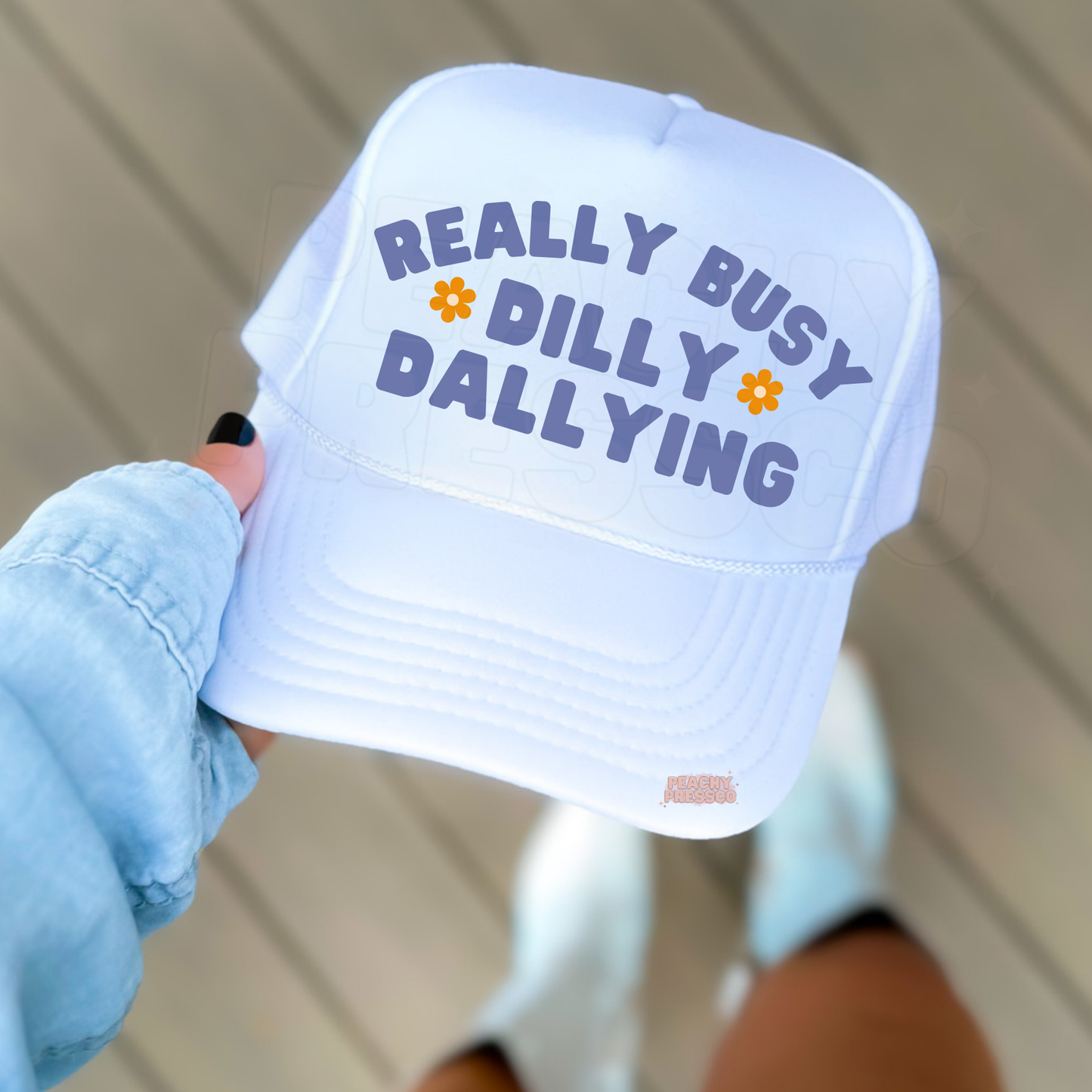 White trucker hat with blue “Really Busy Dilly Dallying” text.
