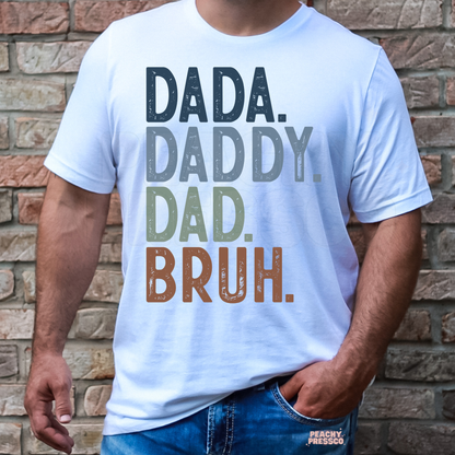 Man wearing white t-shirt with stacked “Dada Daddy Dad Bruh” typography graphic in muted colors.
