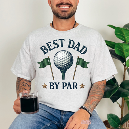 Man sitting indoors wearing ash grey t-shirt with retro “Best Dad By Par” golf Father’s Day design.