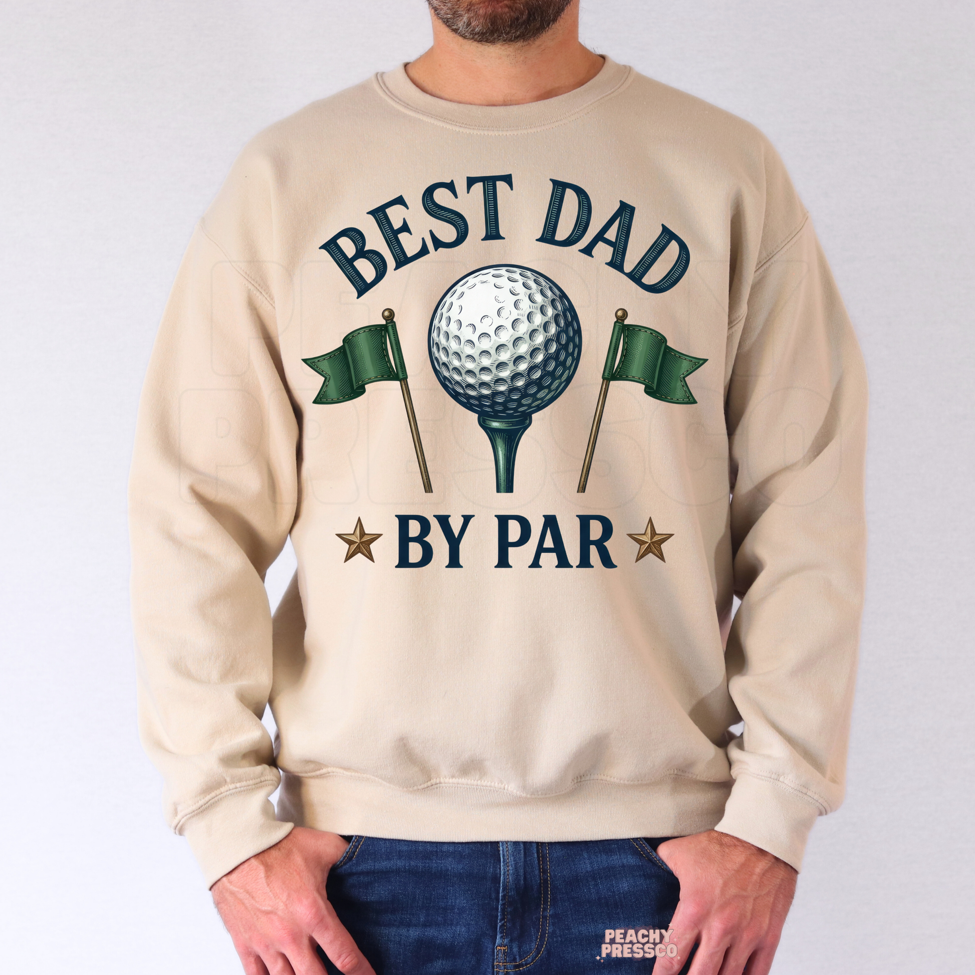 Man wearing beige sweatshirt with golf-inspired “Best Dad By Par” graphic featuring golf ball, flags, and vintage typography.