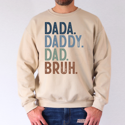 Man wearing beige crewneck sweatshirt featuring colorful “Dada Daddy Dad Bruh” funny Father’s Day design.