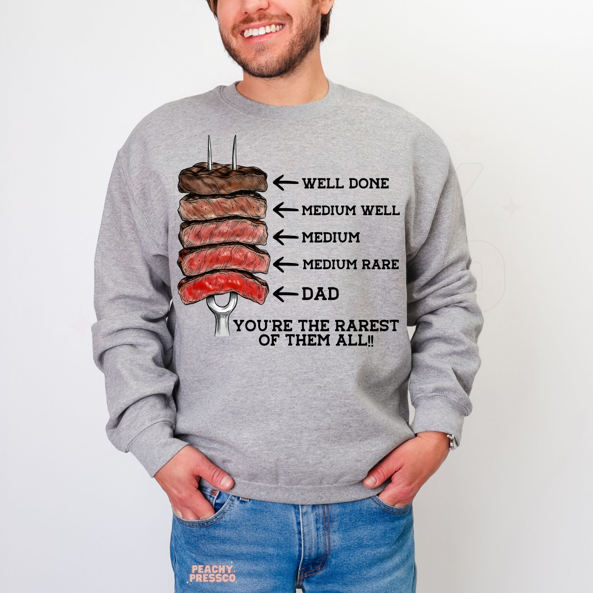 Man modeling grey crewneck sweatshirt with steak doneness chart graphic and funny dad-themed barbecue design.