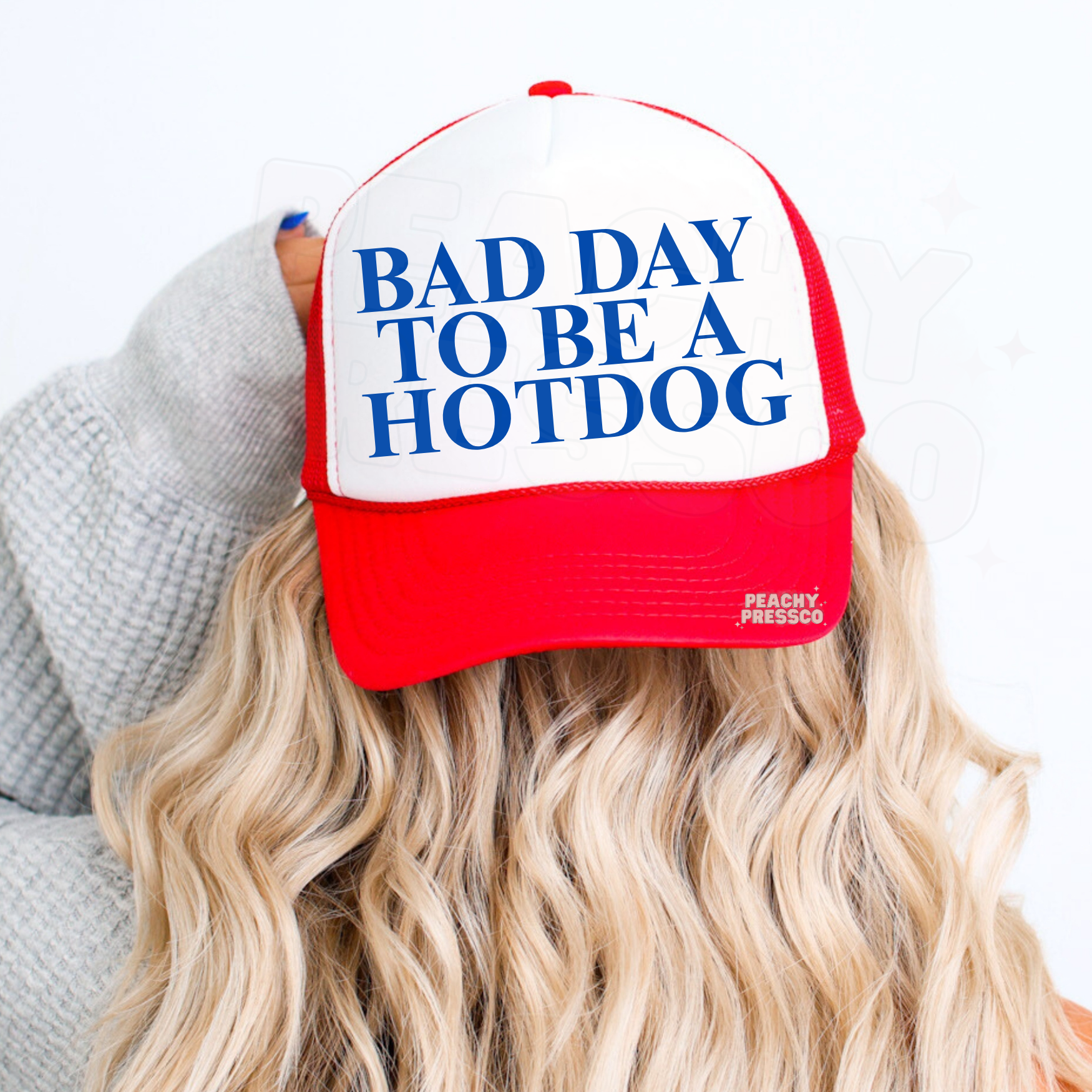 Red and white retro trucker hat with blue “BAD DAY TO BE A HOTDOG” graphic. Funny summer trucker hat aesthetic.