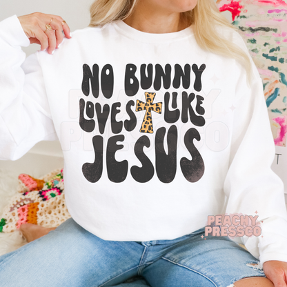 White crewneck sweatshirt featuring a No Bunny Loves Like Jesus Christian Easter graphic with bold lettering and leopard cross.