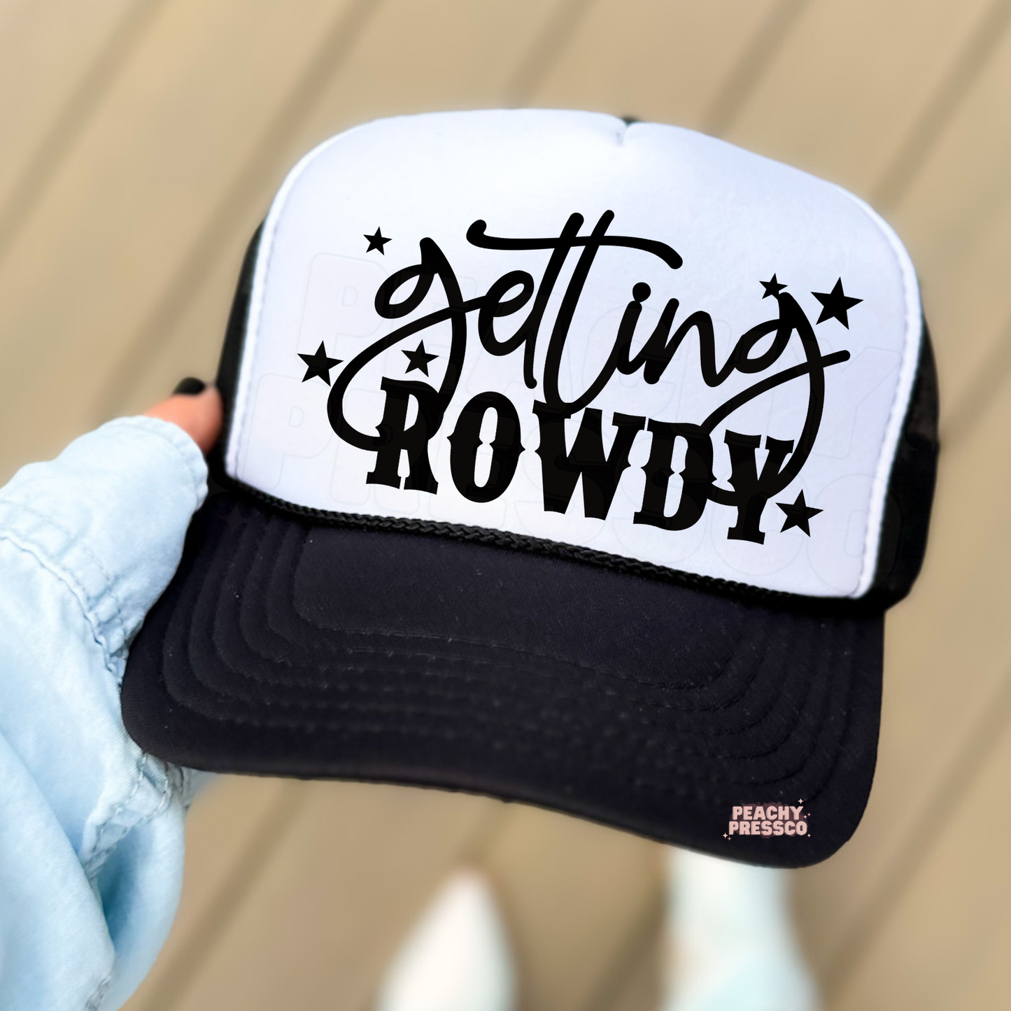 Black and white trucker hat with “Get In Howdy” western typography.
