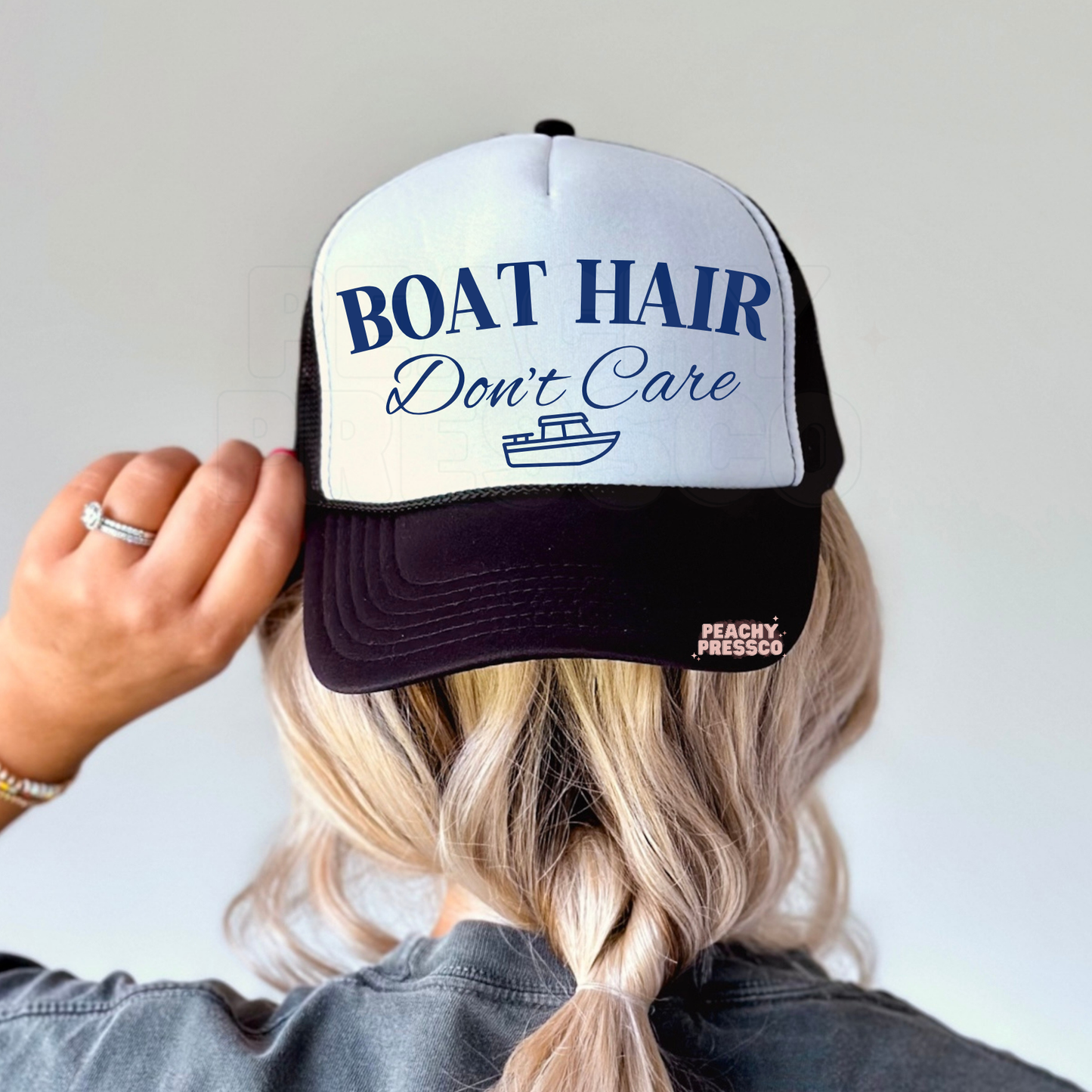 Black and white trucker hat featuring Boat Hair Don’t Care and small boat graphic.