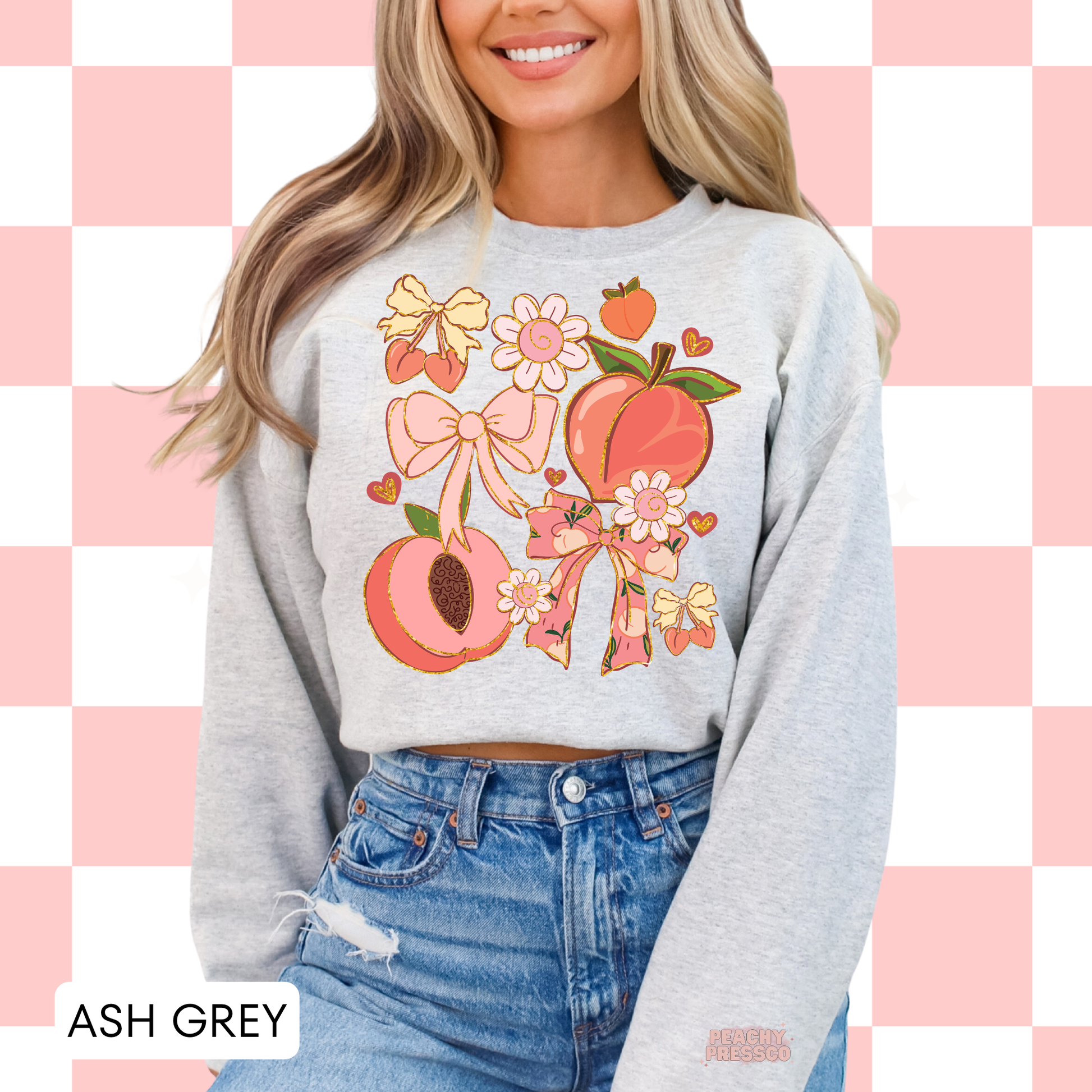 Woman wearing an ash grey sweatshirt with pink peach and bow graphic in a cute retro coquette style.