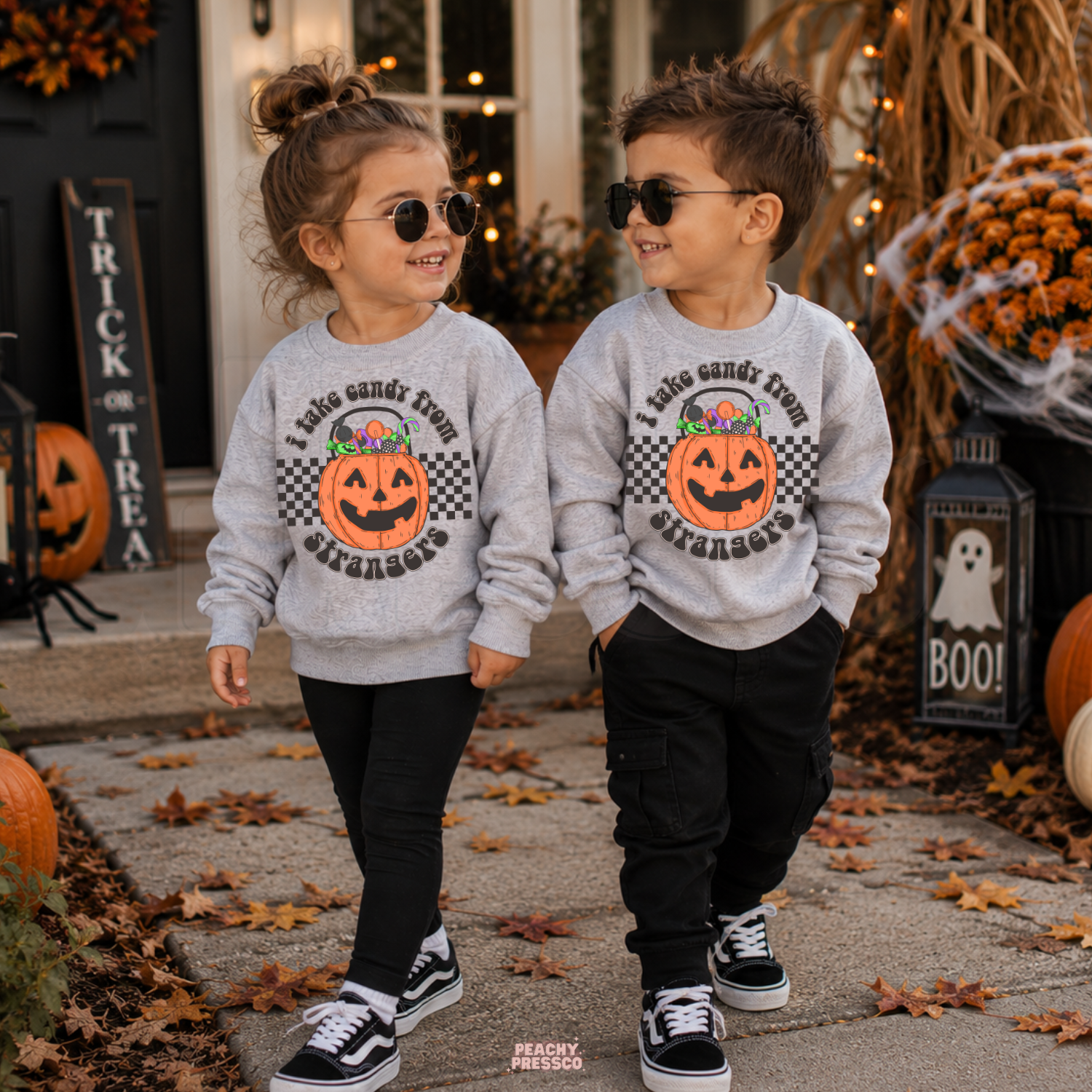 Girl and boy wearing a sport grey Halloween sweatshirts with I Take Candy From Strangers pumpkin candy bucket graphic.
